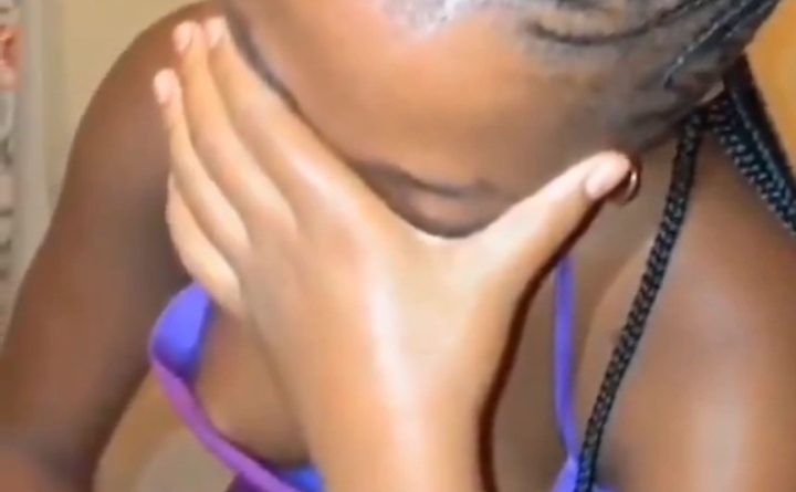 A young Nigerian female TikToker looking worried while holding her phone as social media notifications flood in.